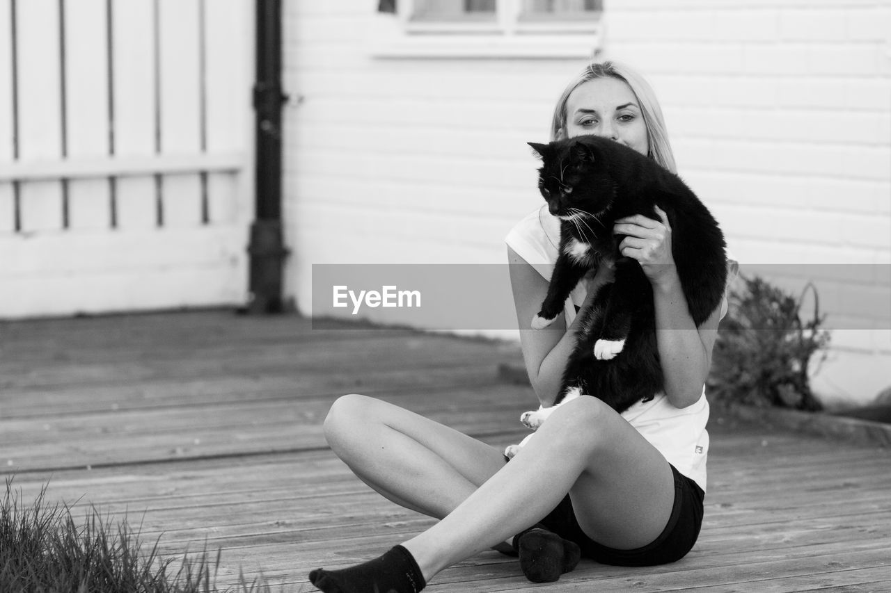 Portrait of teenage girl playing with cat outdoors
