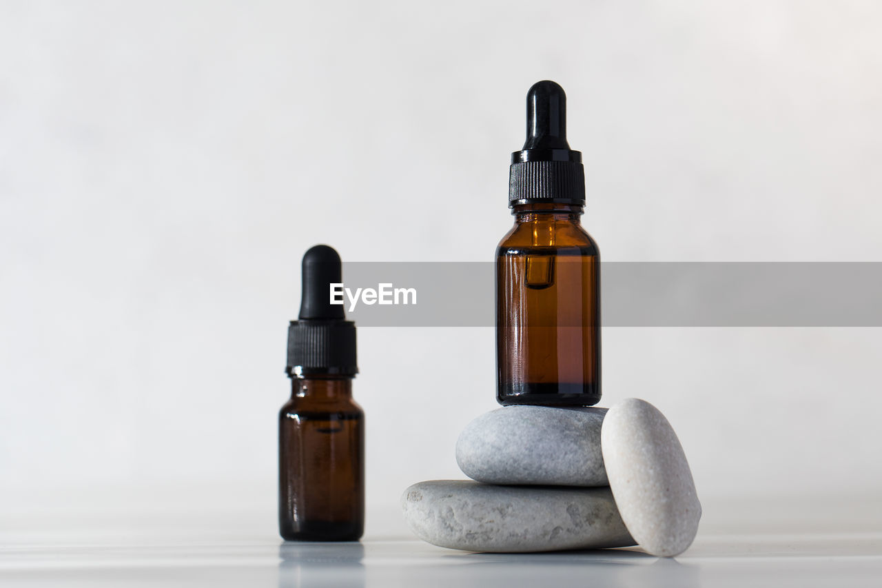 Brown glass bottles with skin oil on stones on a light background.