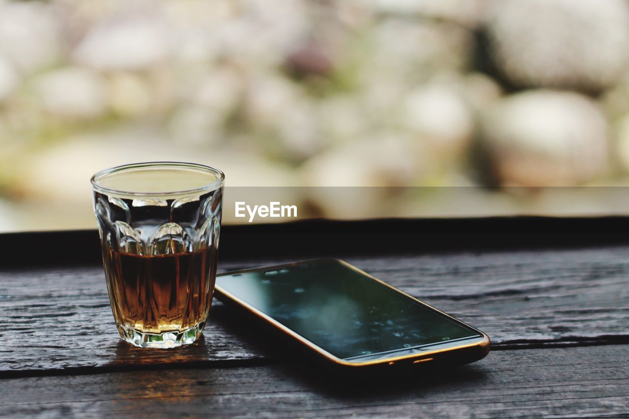 Close-up of drink and smart phone on wooden table