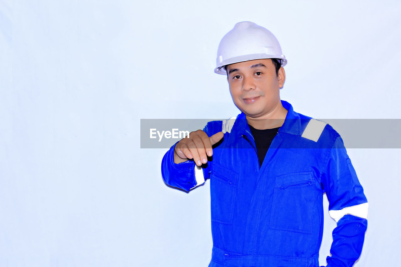 Portrait of smiling man standing against blue background