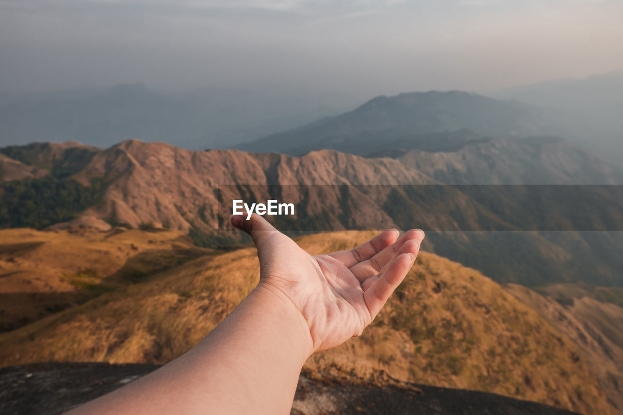 Midsection of person on mountain against sky