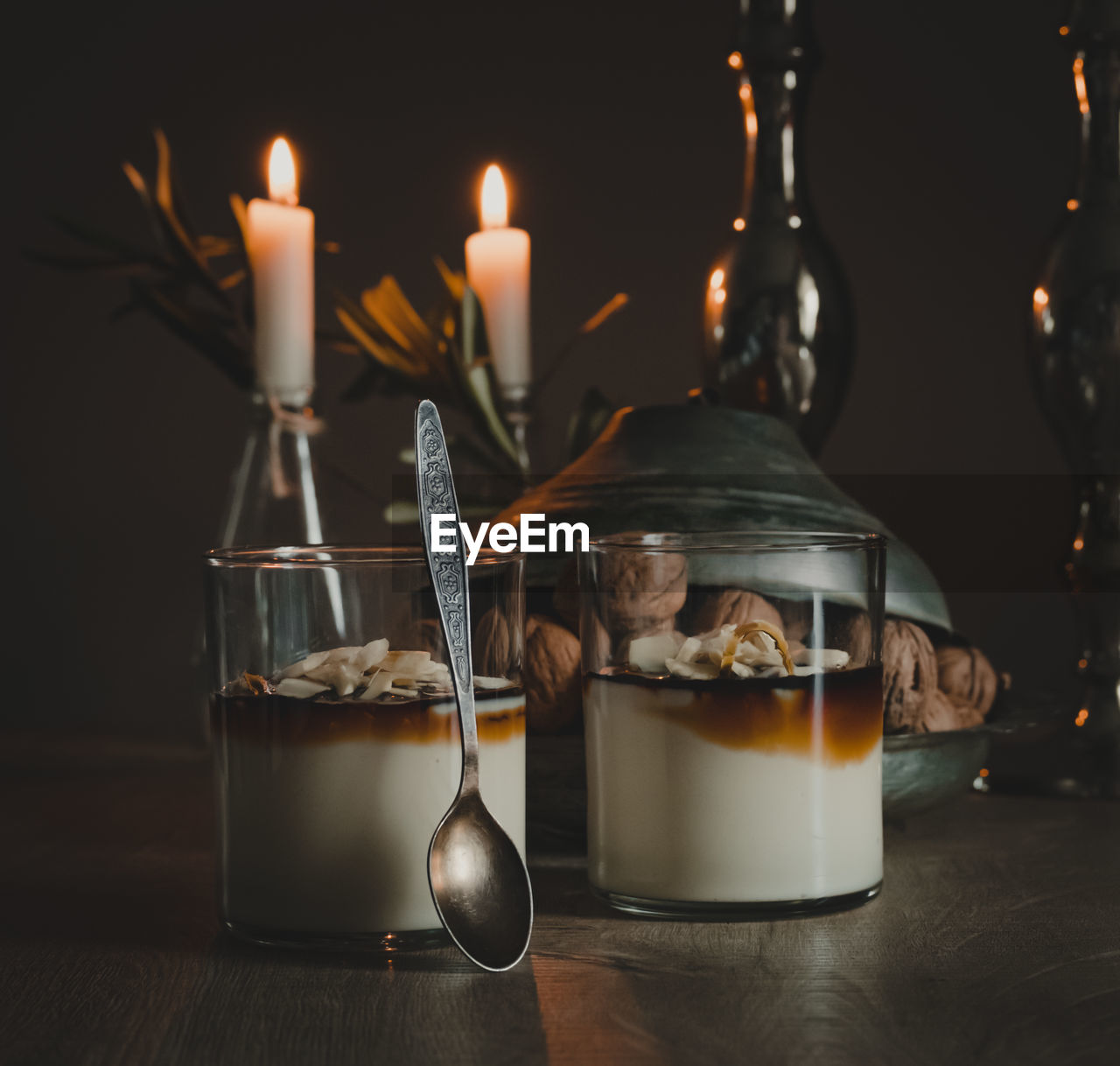 Two cups of tahini custard dessert on the table with candles in the background.