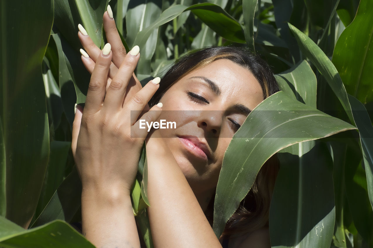 Close-up portrait of young woman with leaves