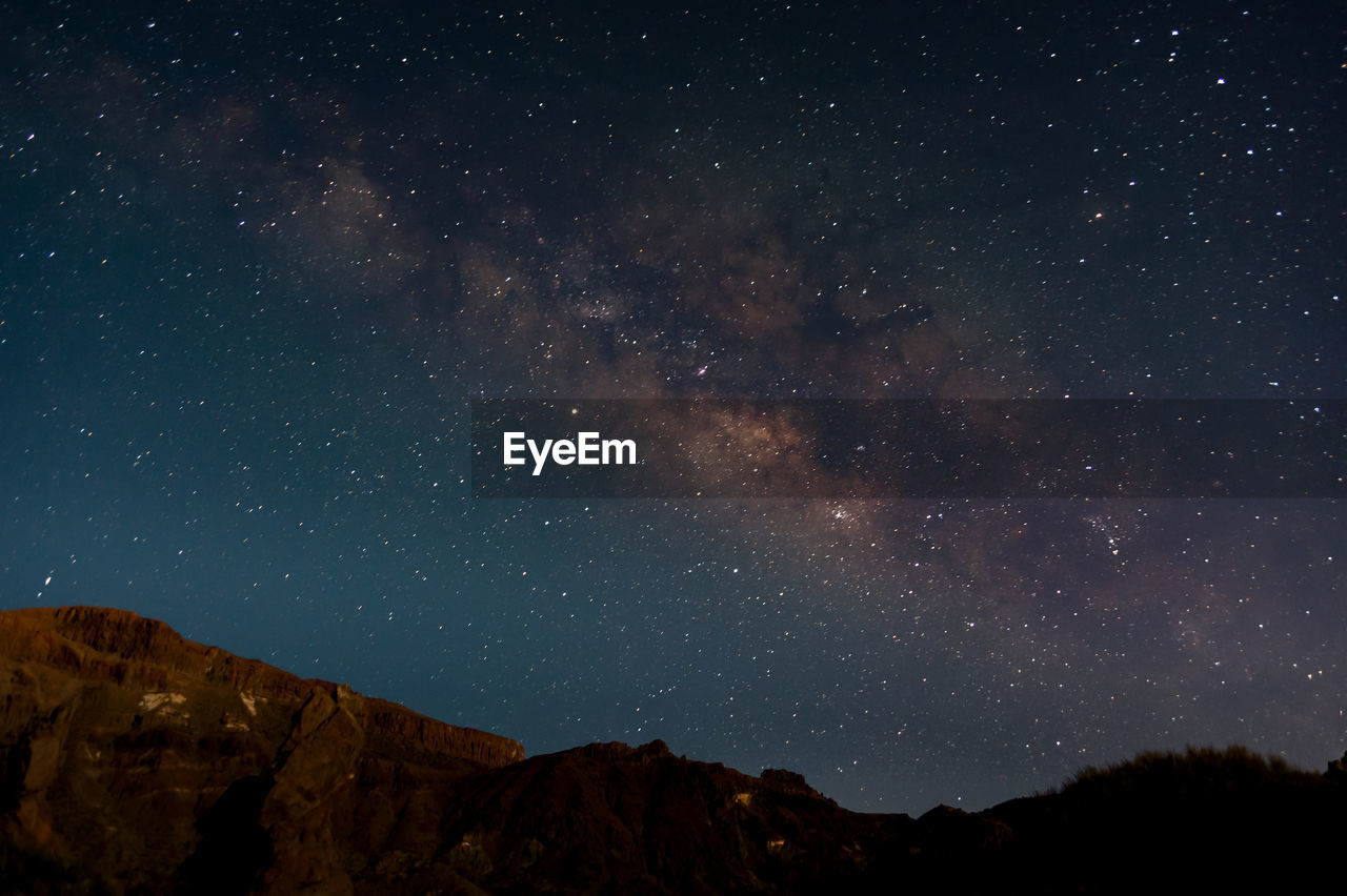 Low angle view of silhouette mountain against sky at night