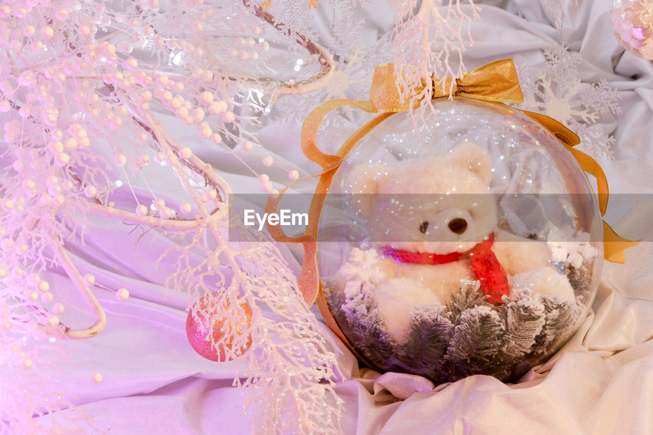 High angle view of christmas decorations in snow - teddy bear inside a bubble glass