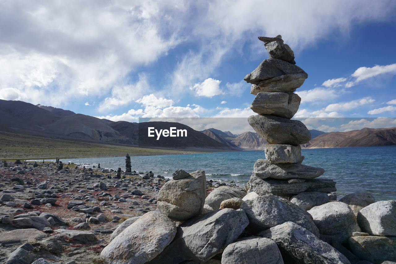 Stack of pebbles on shore against sky