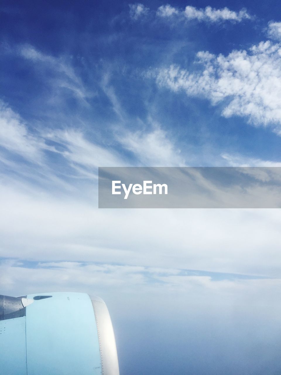 Cropped jet engine of airplane against cloudy sky