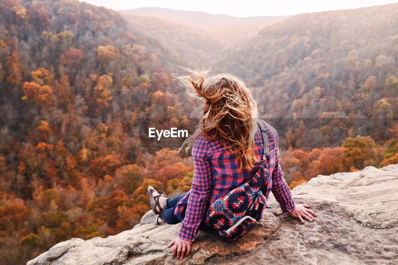 WOMAN WITH DOG SITTING ON MOUNTAIN ROAD DURING AUTUMN