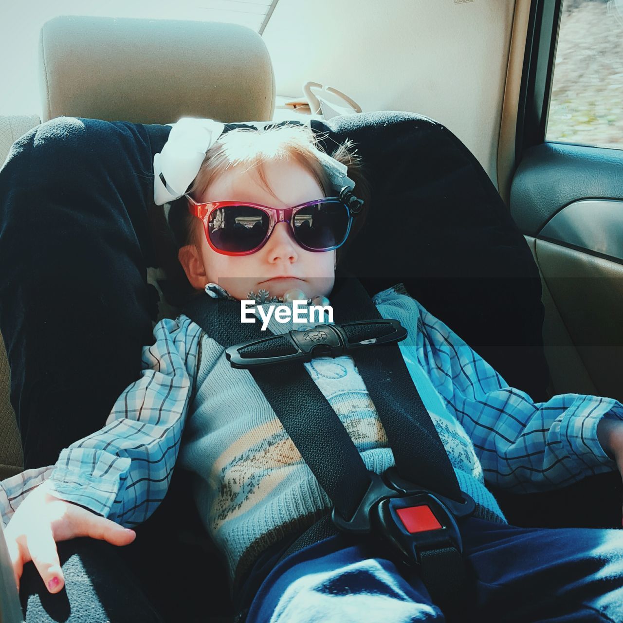 Portrait of girl wearing sunglass relaxing on seat in car