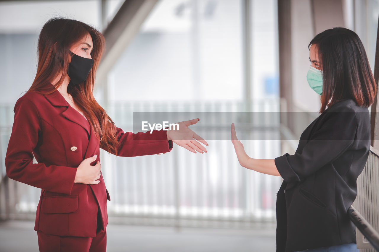 Woman giving handshake to female showing stop sign