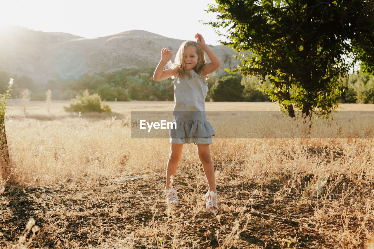 Portrait of smiling girl standing on grassy field against mountain