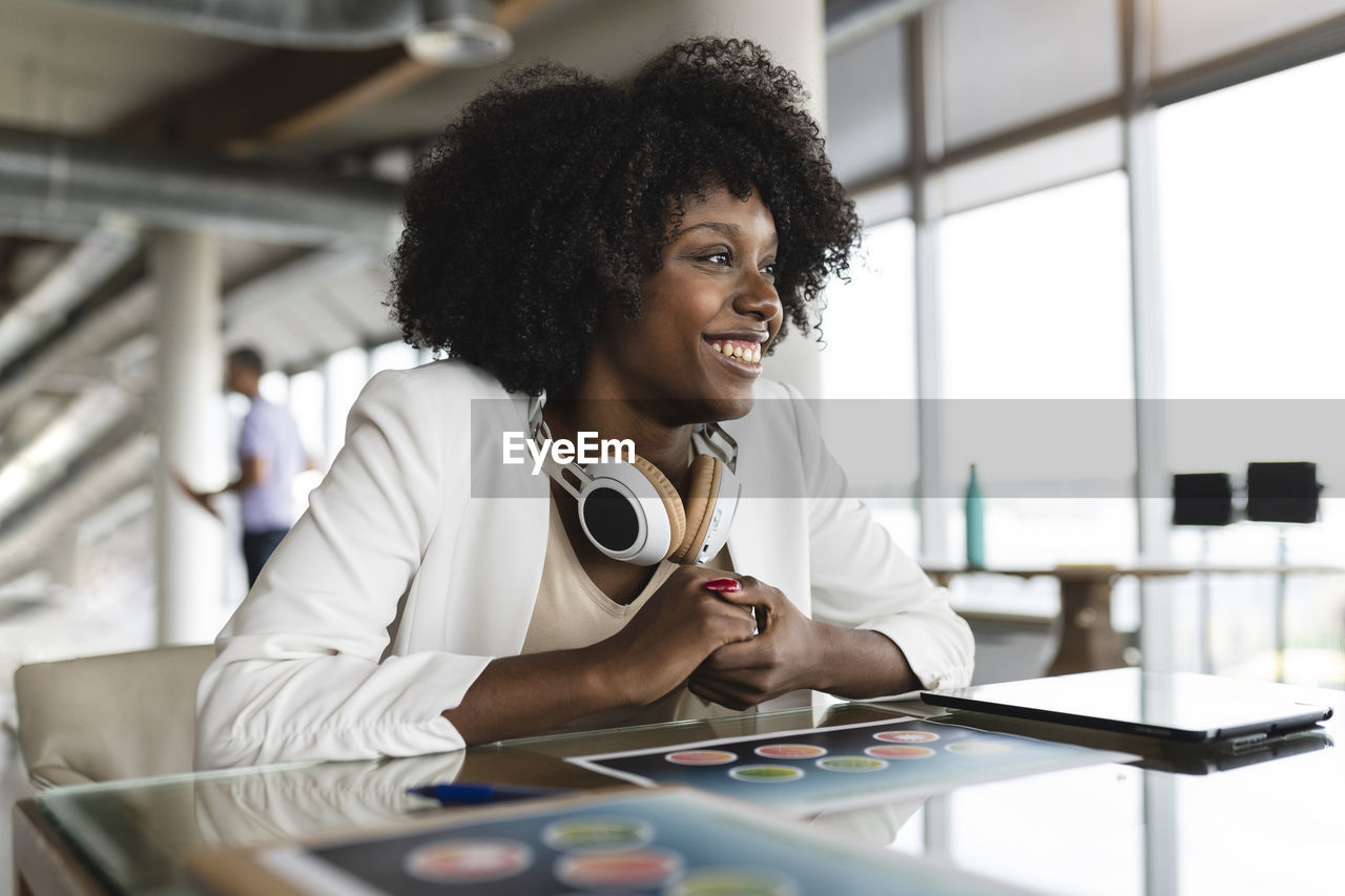 Businesswoman with wireless headphones sitting at desk