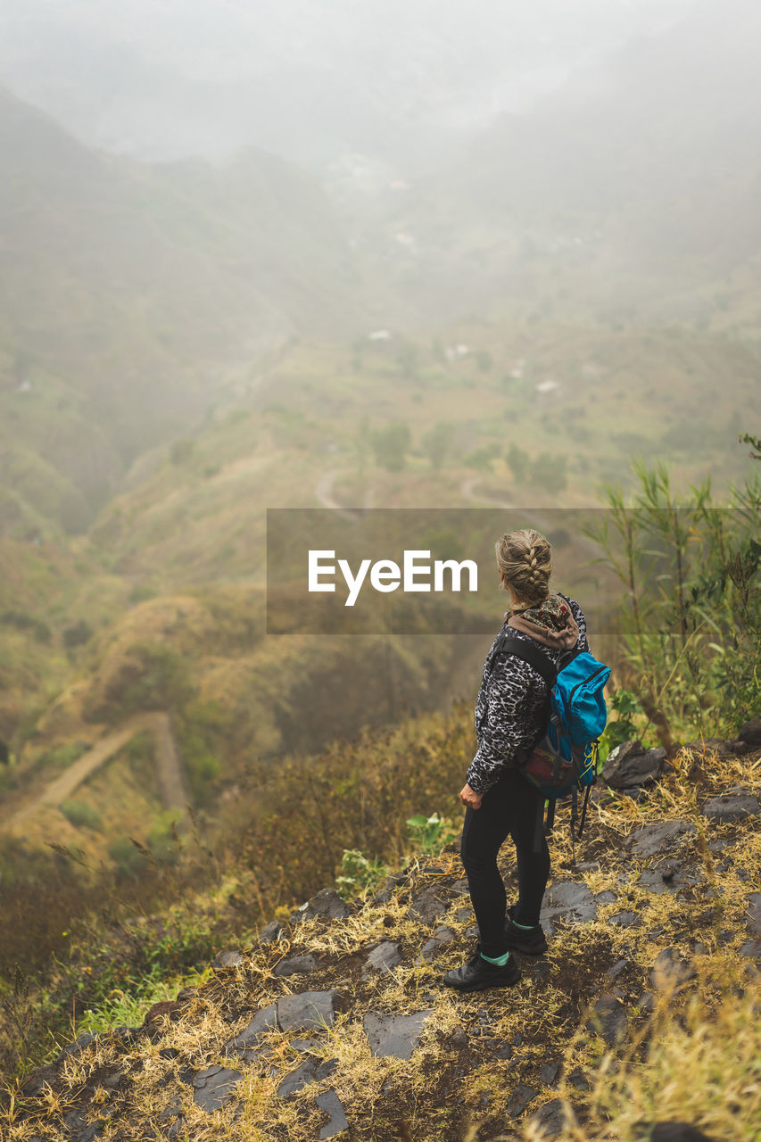 High angle view of woman standing by cliff looking at view