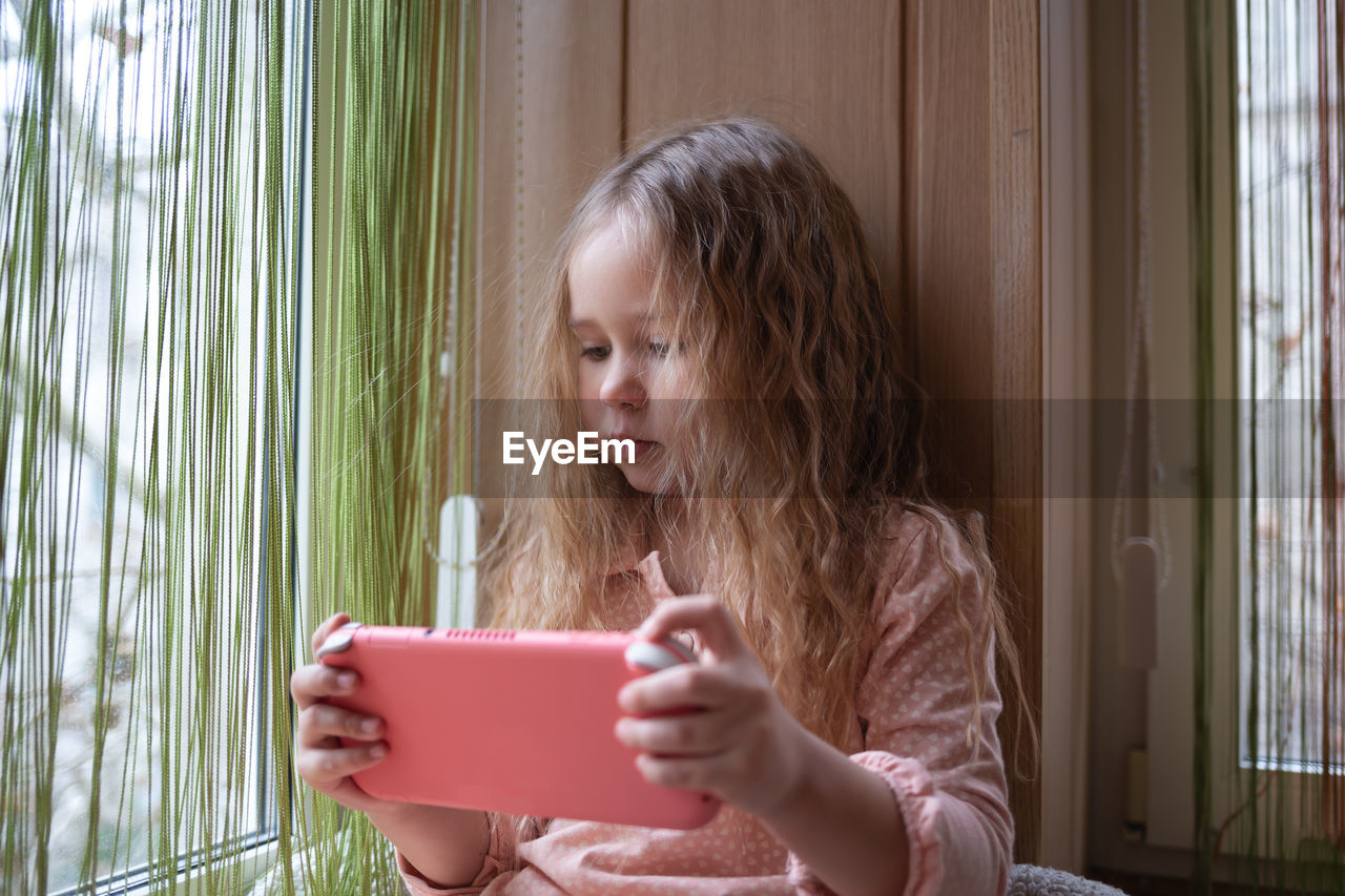 young woman using mobile phone while sitting at home