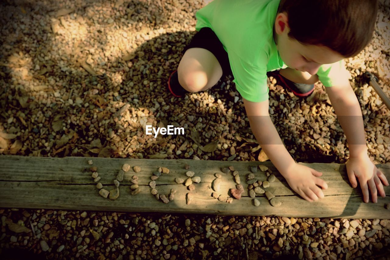 Young boy playing with pebbles in a park