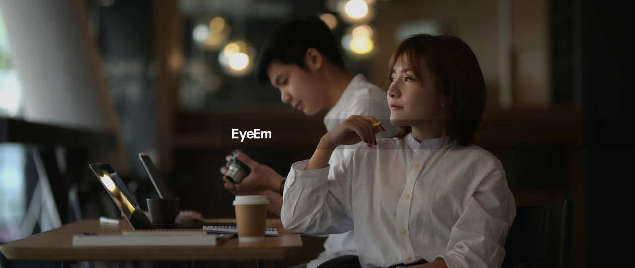 Thoughtful businesswoman sitting with male colleague in office