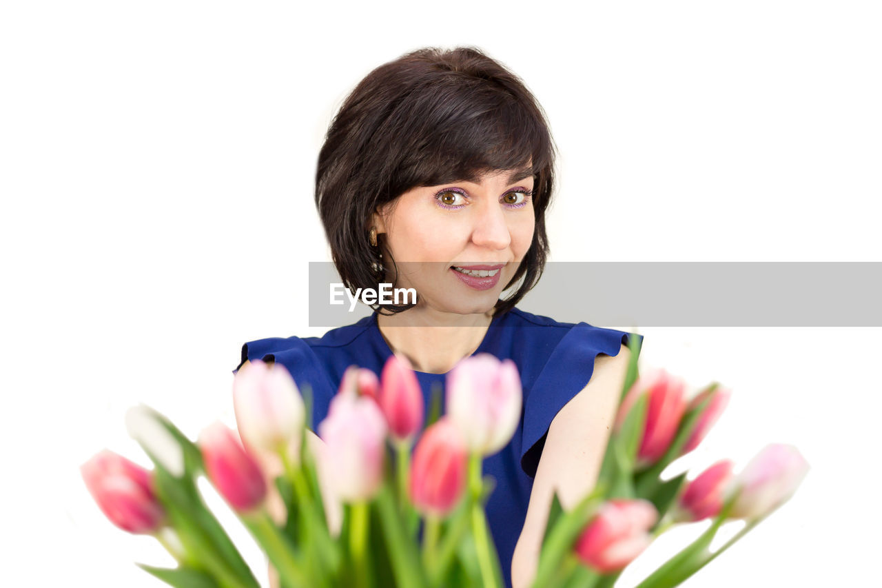 flower, flowering plant, plant, one person, women, beauty in nature, tulip, portrait, adult, white background, freshness, person, smiling, studio shot, nature, indoors, female, emotion, cut out, happiness, human face, floristry, young adult, cheerful, headshot, copy space, looking at camera, bouquet, lifestyles, clothing, brown hair, positive emotion, springtime, front view, bunch of flowers, cut flowers, fragility