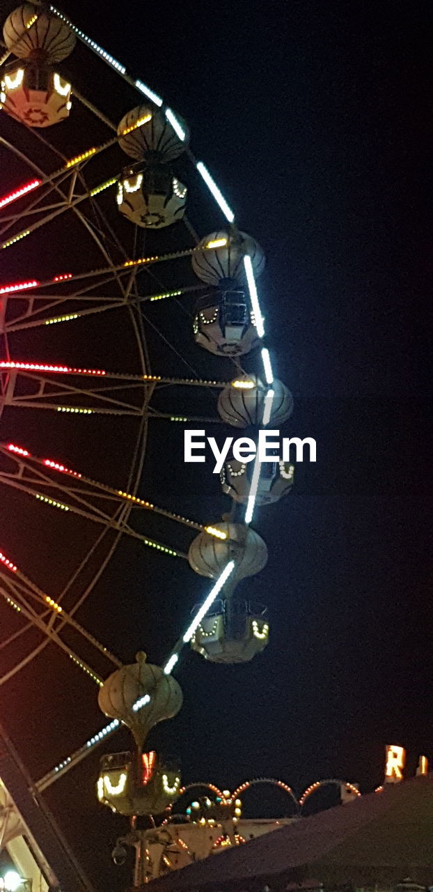 LOW ANGLE VIEW OF ILLUMINATED FERRIS WHEEL AGAINST CLEAR SKY