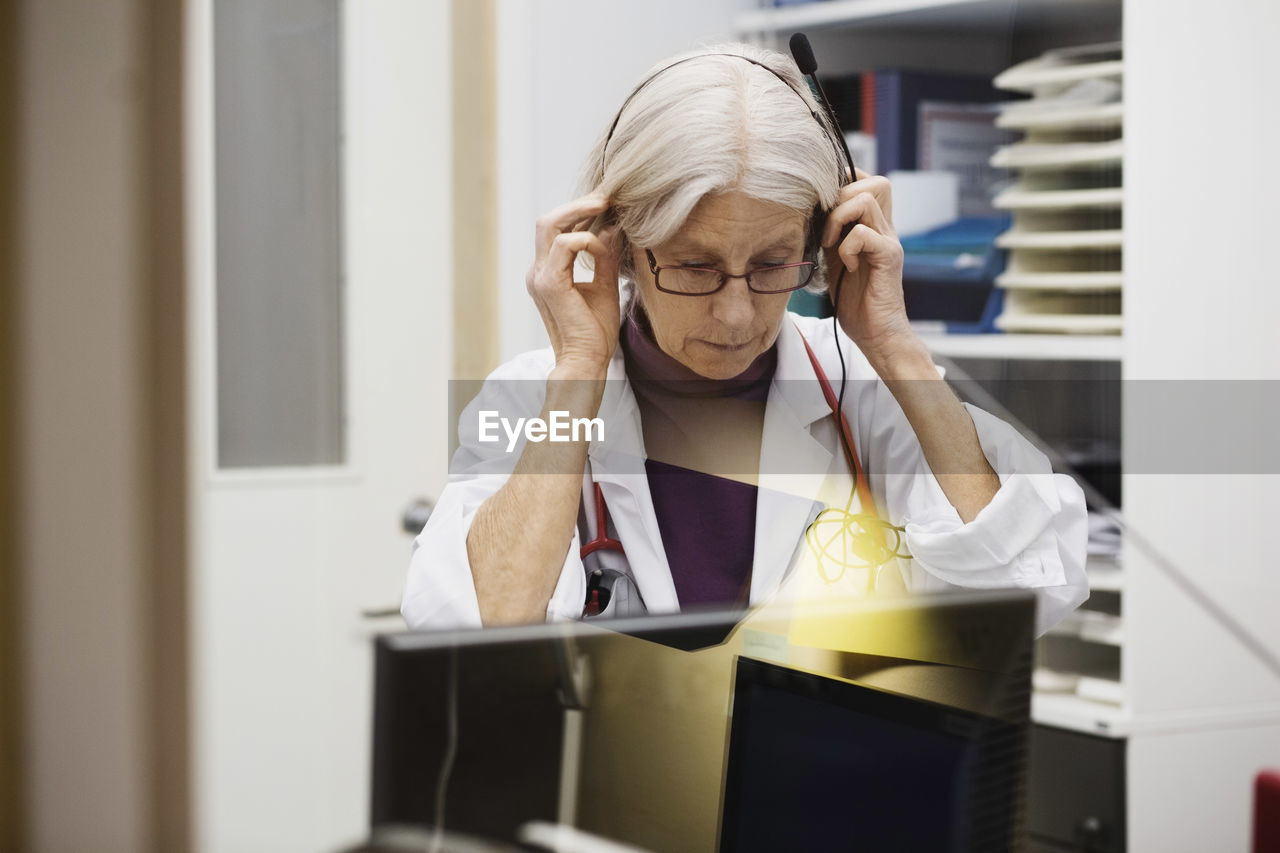 Senior female audiologist wearing headphones in examination room