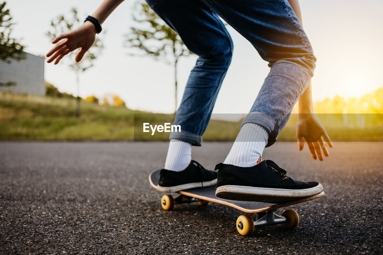 LOW SECTION OF MAN SKATEBOARDING ON SKATEBOARD