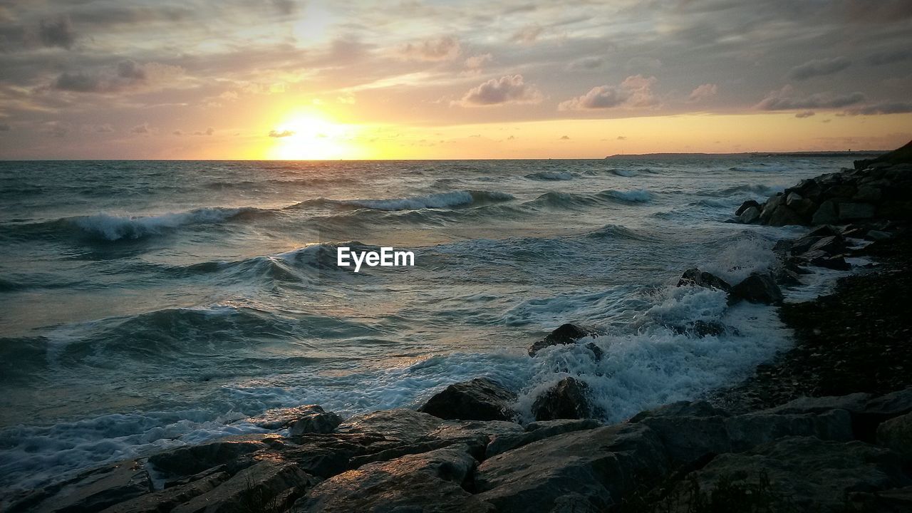 SCENIC VIEW OF BEACH AGAINST DRAMATIC SKY