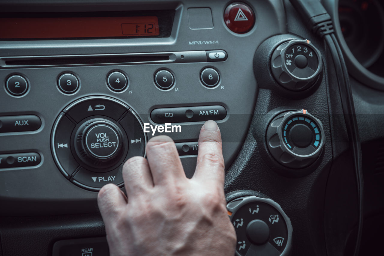 Cropped hand of man playing music in car