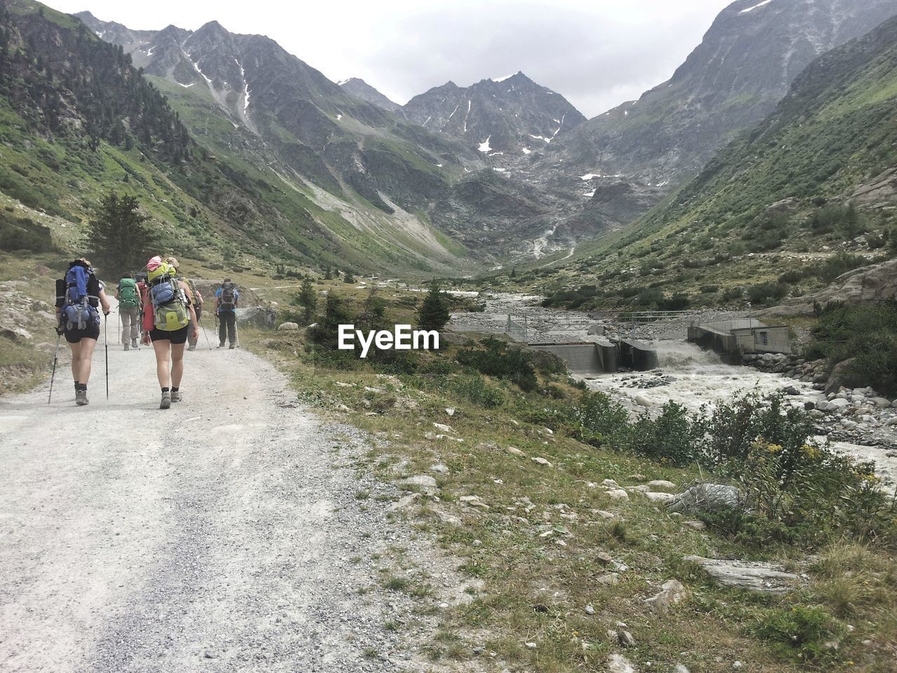 PEOPLE WALKING ON ROAD BY MOUNTAINS