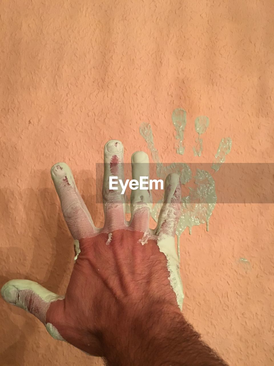Man with paint on hand against wall