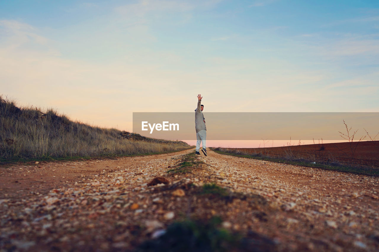 Man standing on road against sky during sunset