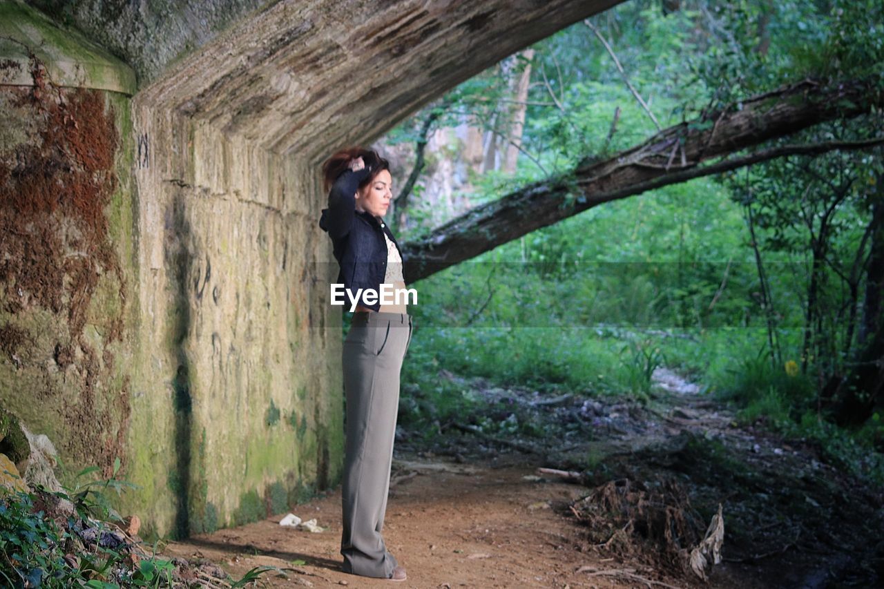 Woman standing under bridge in forest