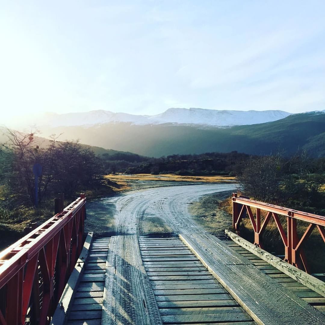 Tire tracks on road and bridge against mountains