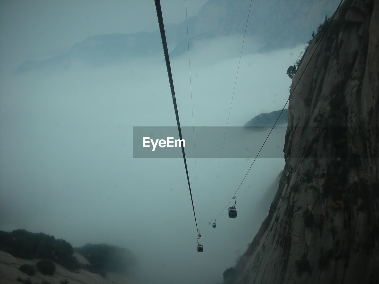 LOW ANGLE VIEW OF HANGING FROM MOUNTAIN AGAINST SKY