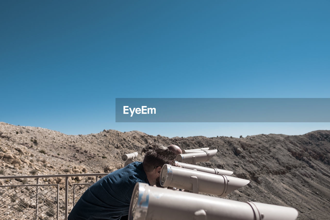 Man standing at observation point against clear blue sky