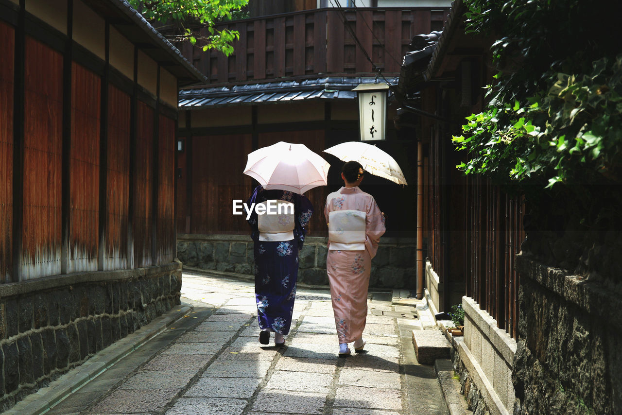 REAR VIEW OF TWO PEOPLE WALKING ON STREET