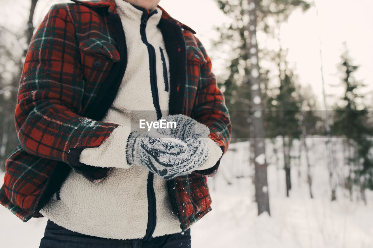 Midsection of man making snowball on snowy field at park