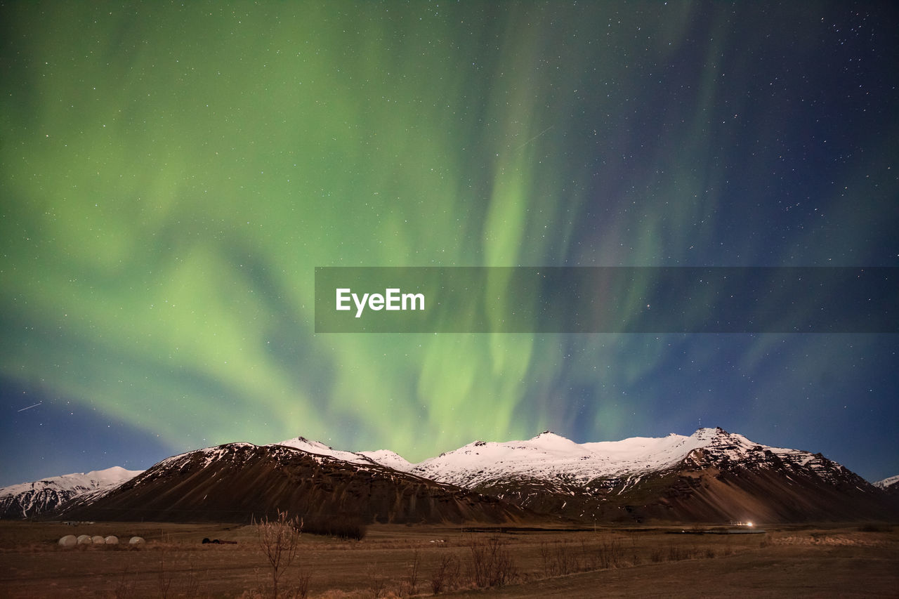 Scenic view of snowcapped mountains against aurora borealis at night