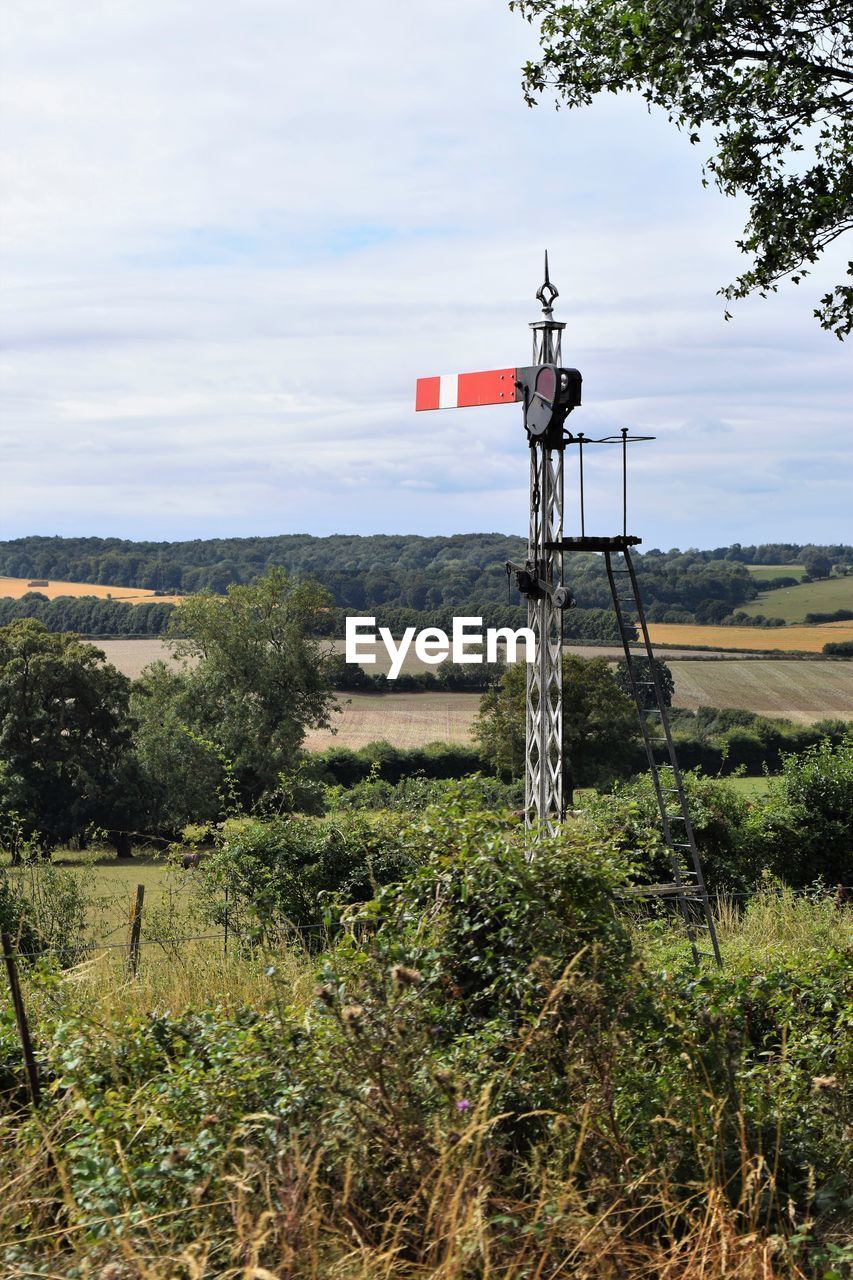 Old railway signal on field against sky