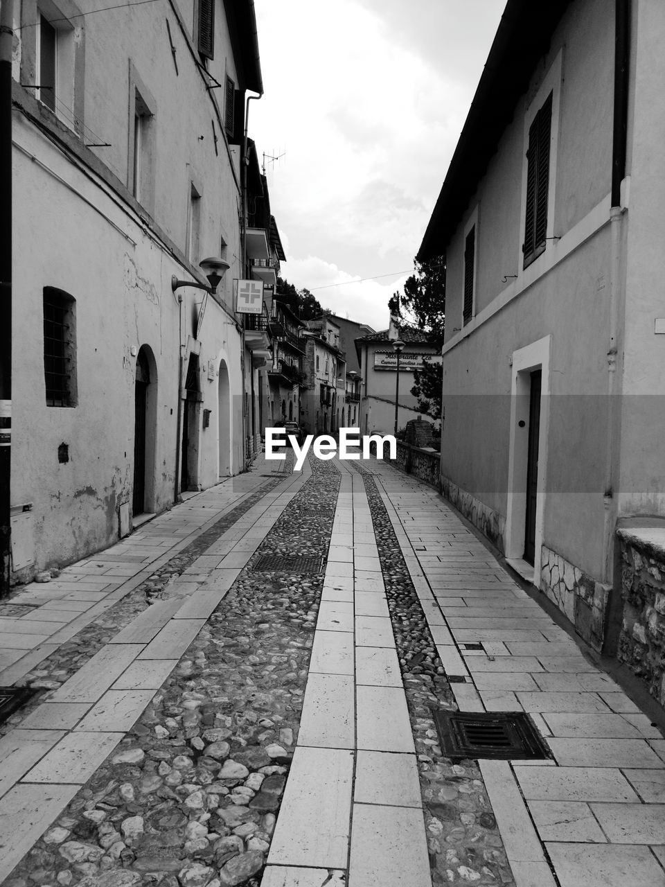 EMPTY ROAD AMIDST BUILDINGS IN CITY