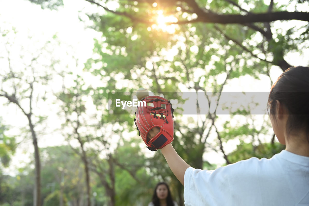 side view of man holding lantern against trees