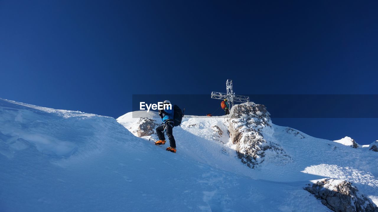 Low angle view of man on snowcapped mountain against sky