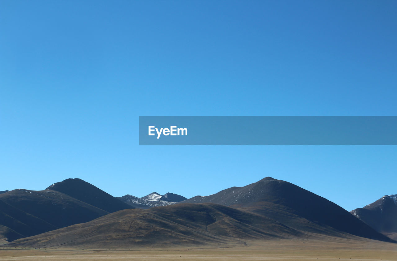 Scenic view of mountains against clear blue sky