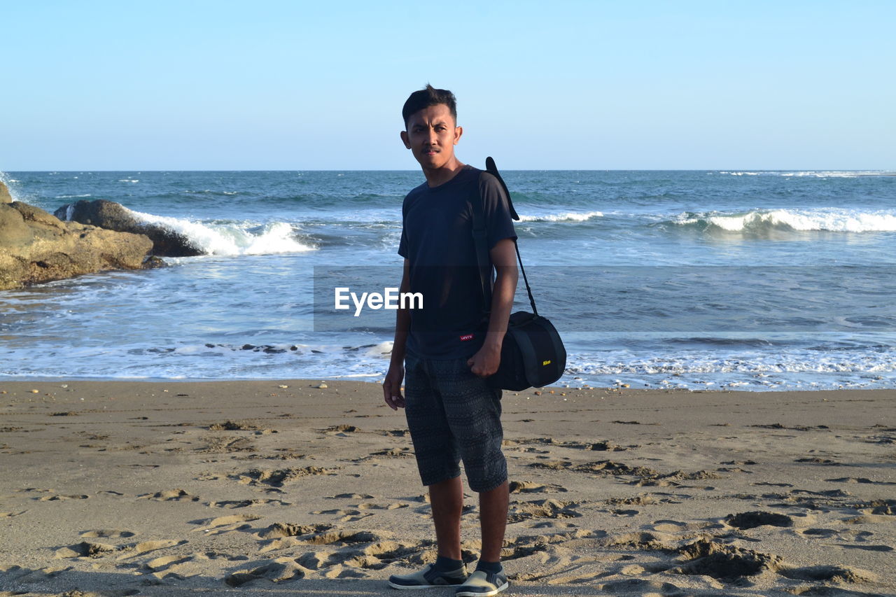 Full length of man standing on beach against sky