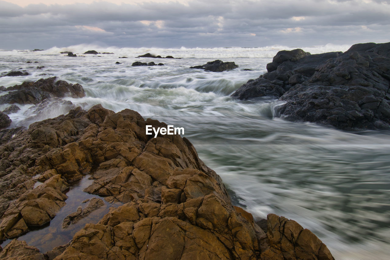 Long exposure view of rocks in sea against sky