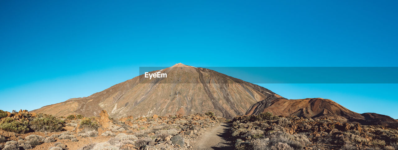 Scenic view of desert against clear blue sky