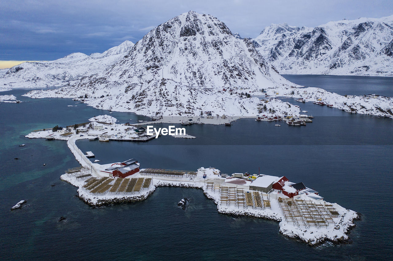 Scenic view of snow covered mountain by sea against sky