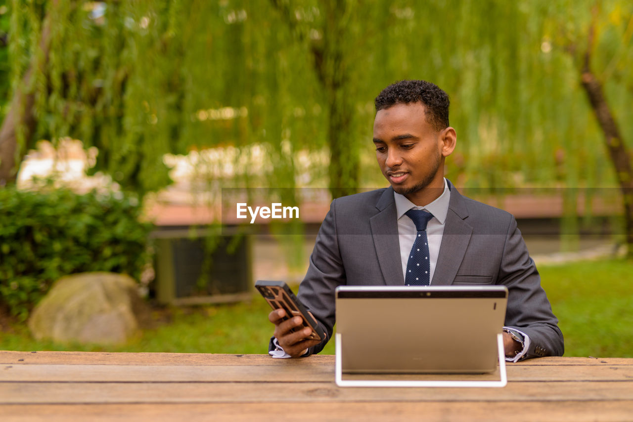 Man using mobile phone while sitting on table