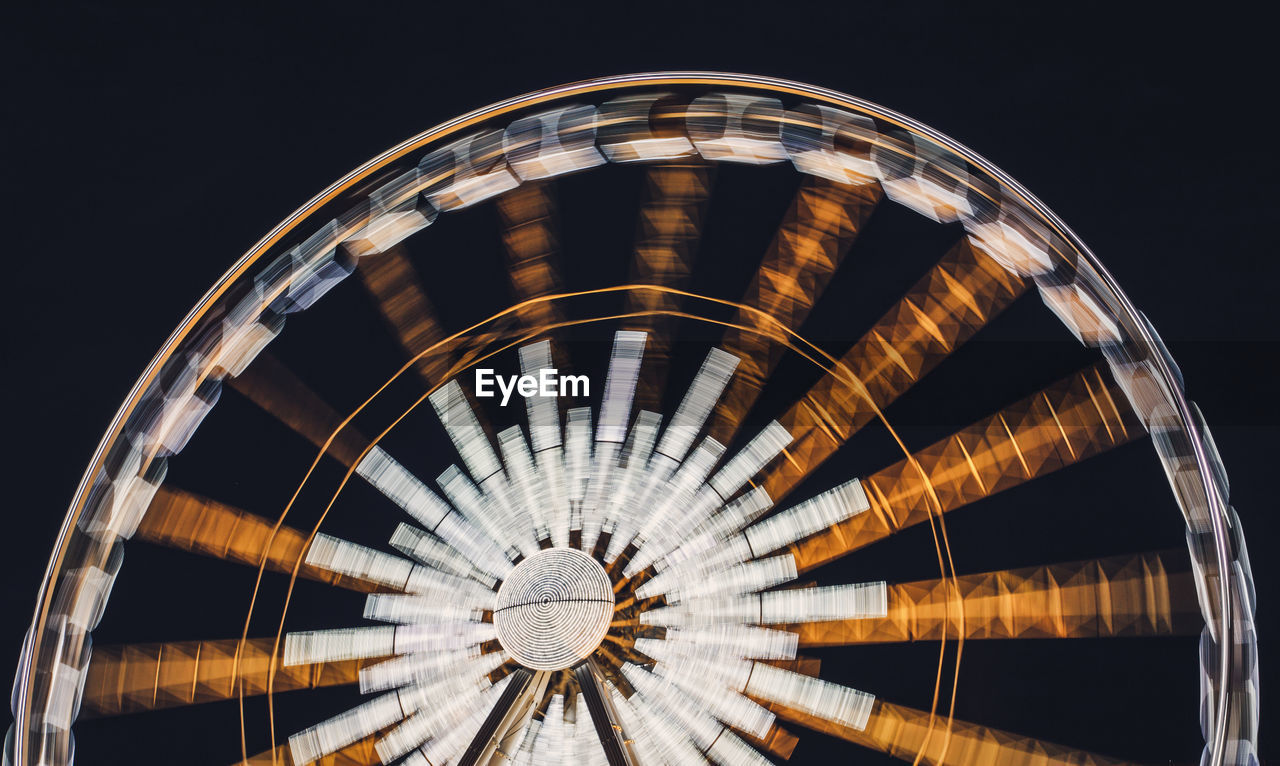 Low angle view of built structure at night and ferris wheel