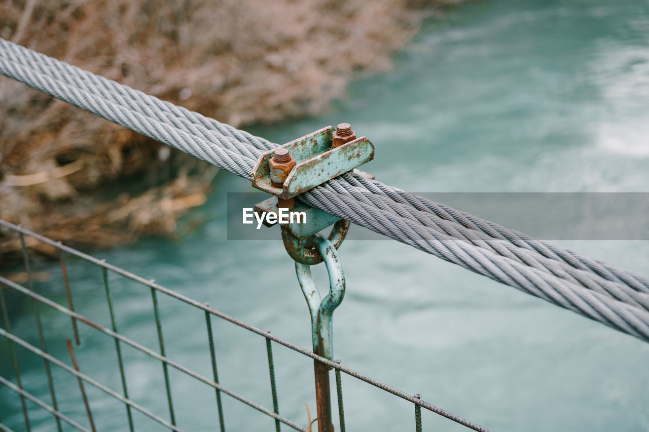 Close-up of rope tied to metal fence