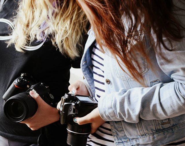 PERSON HOLDING CAMERA WHILE STANDING ON WHITE BACKGROUND