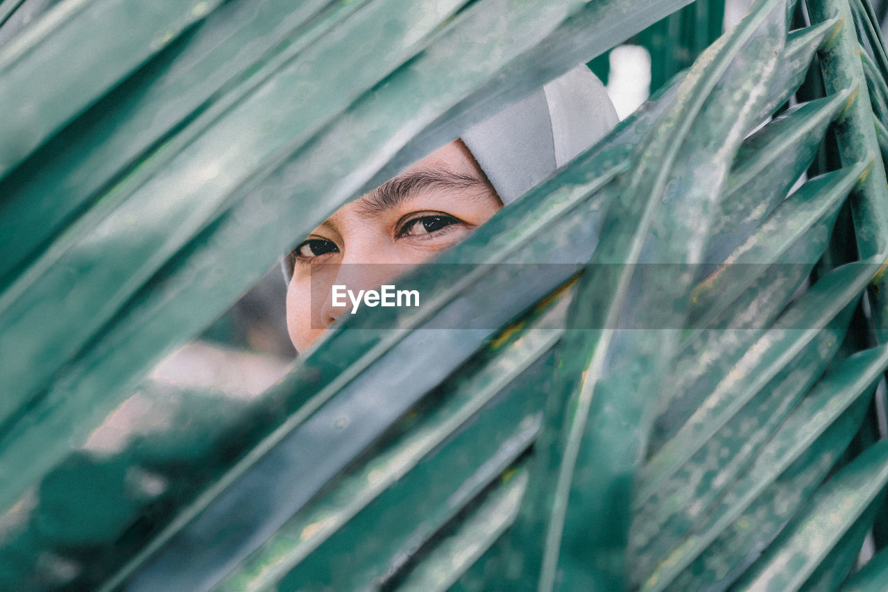 Portrait of a woman behind palm leaves